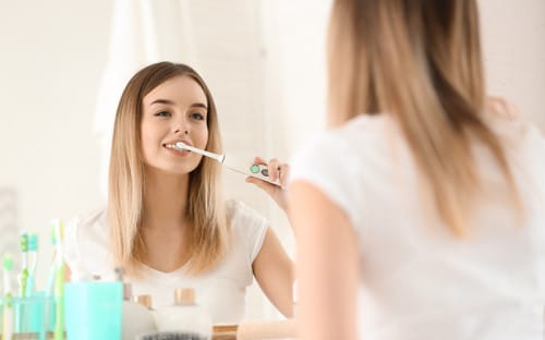 Woman using electric toothbrush
